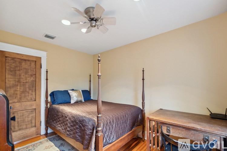 A bedroom with a bed, dresser, and ceiling fan.