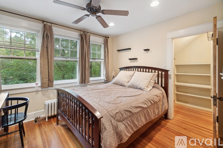 A bedroom with a bed, chair, and window.