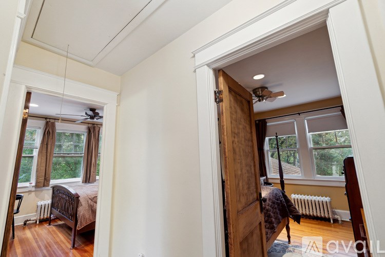 A bedroom with a bed, a window with a fan, and a wooden door.