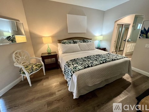 A bedroom with a large bed and a chair.