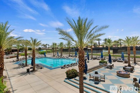 A pool surrounded by palm trees and lounge chairs.