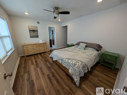 A bedroom with a bed, dresser, and ceiling fan.