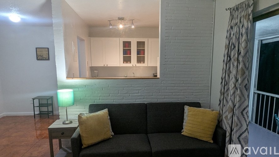 A living room with a grey couch and a green lamp.