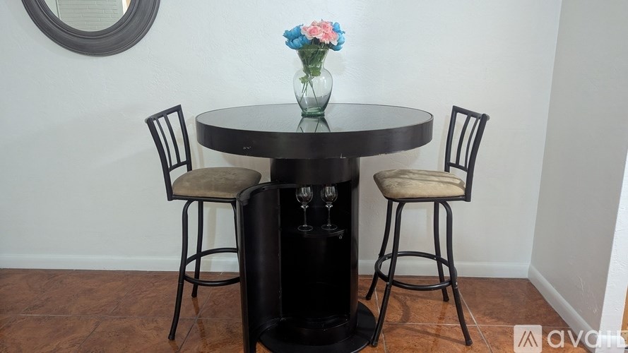 A black table with a vase of flowers and two chairs.