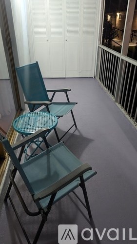 Two chairs and a table are on a balcony.