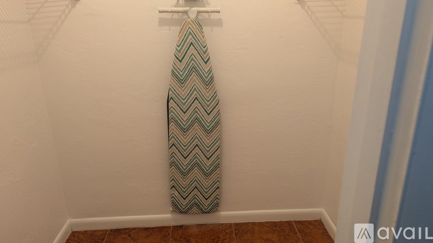 A tie with a chevron pattern hangs on a white wall.
