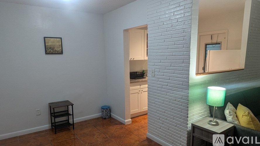 A room with a white brick wall and a mirror on the right side.