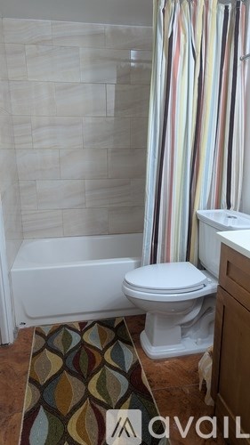 A white toilet in a bathroom with a patterned rug.