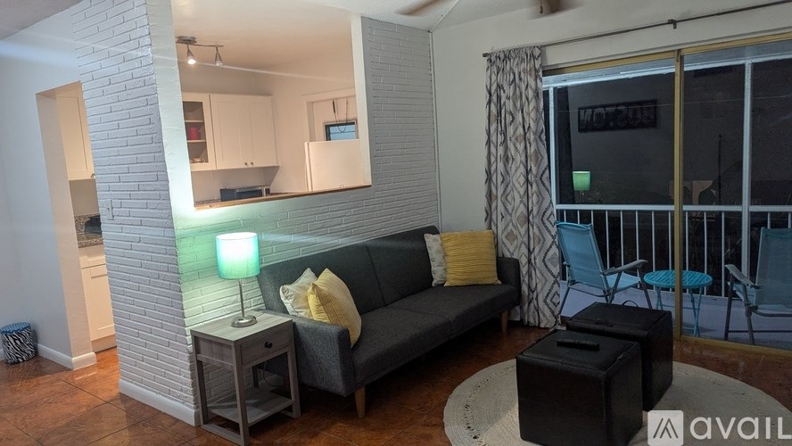 A living room with a grey couch and a lamp on a side table.