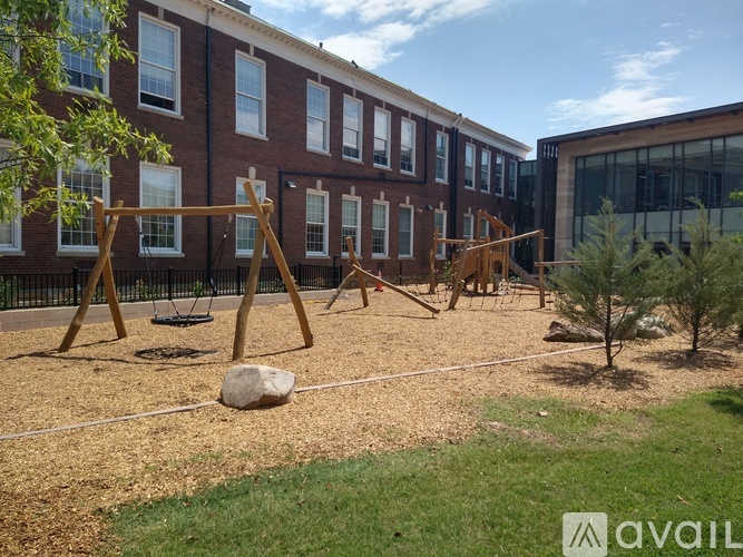 A playground with swings and a slide in front of a brick building.