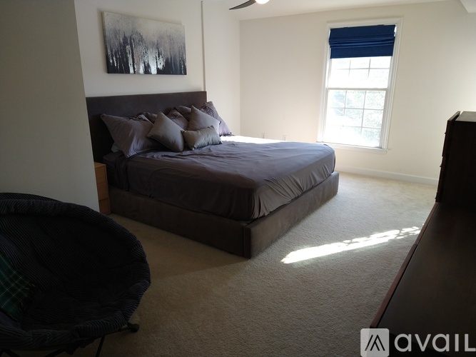 A bedroom with a bed, a chair, and a painting on the wall.