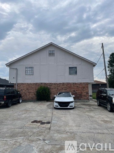 A white car is parked in front of a grey building.