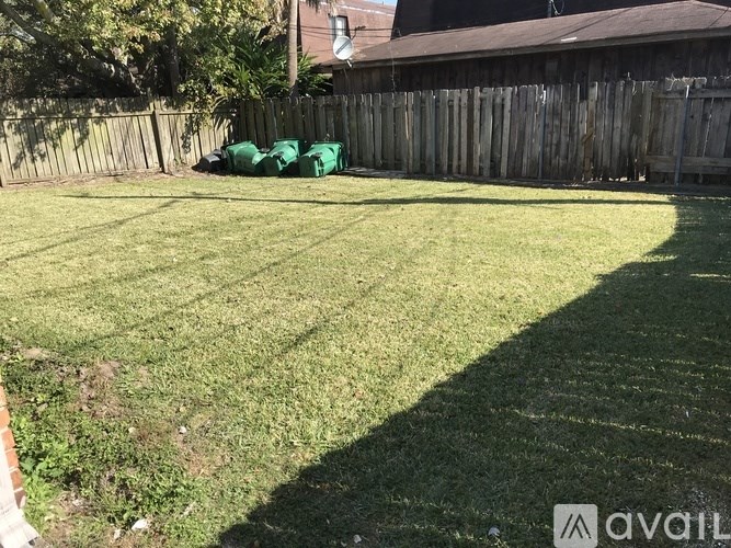 A backyard with a wooden fence and a green lawn.