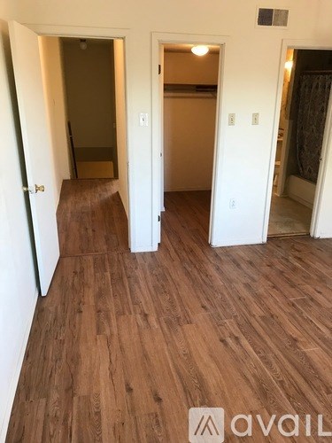 A hallway with wood flooring and white walls.