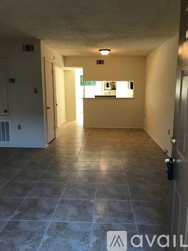 A hallway with tiled floors and a window in the distance.
