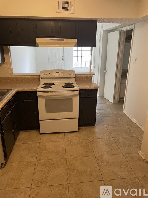 A kitchen with a white stove top oven and black cabinets.