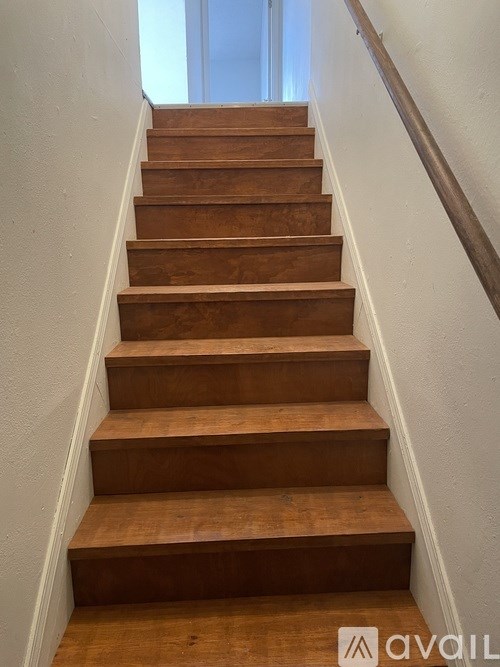 A set of wooden stairs with a metal handrail.