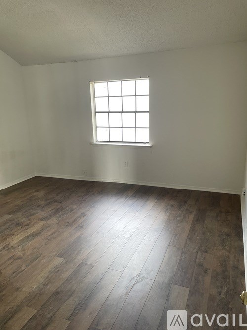 A room with a window and wooden flooring.