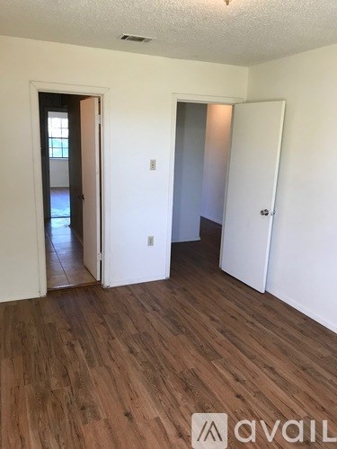 A room with white walls and wood flooring with two doors.