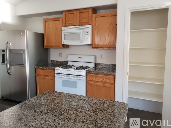 A kitchen with a granite countertop and wooden cabinets.
