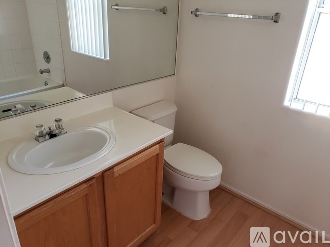 A bathroom with a toilet, sink, and mirror.