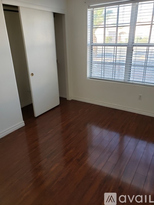A room with wooden floors and a window with blinds.