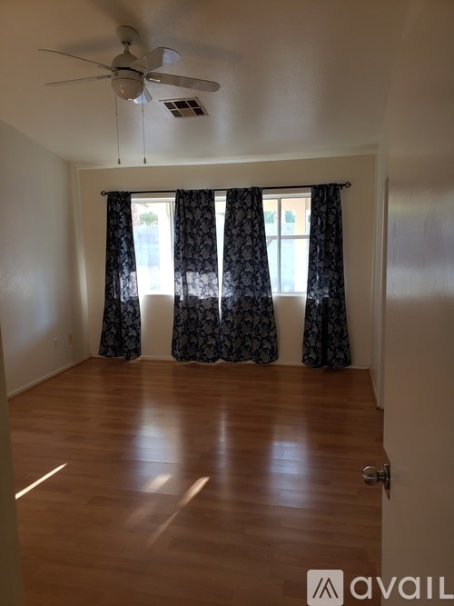 A room with a ceiling fan and a window with curtains.