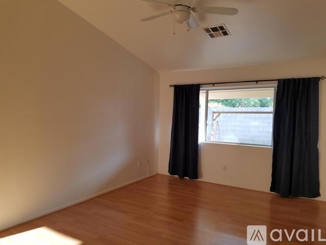 A room with a ceiling fan and a window with black curtains.