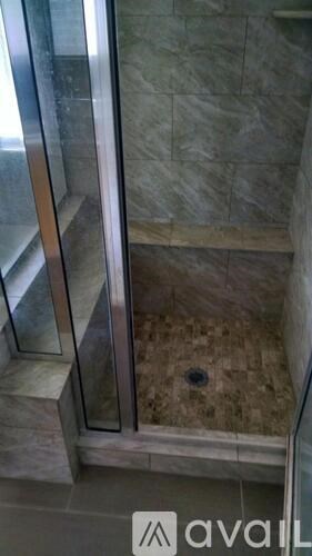 A glass shower door with a drain in the middle.