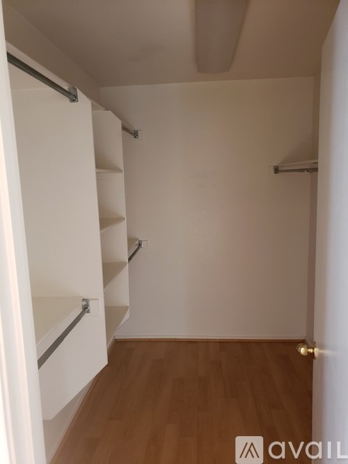 A white closet with a wooden floor and a white door.