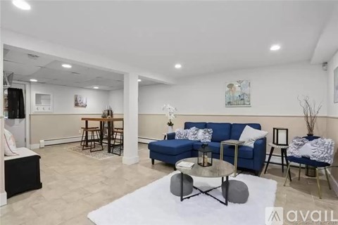 A living room with a blue sofa and a white rug.
