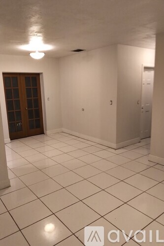 A room with white tiled flooring and a wooden door.