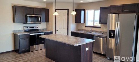 A kitchen with dark brown cabinets and stainless steel appliances.