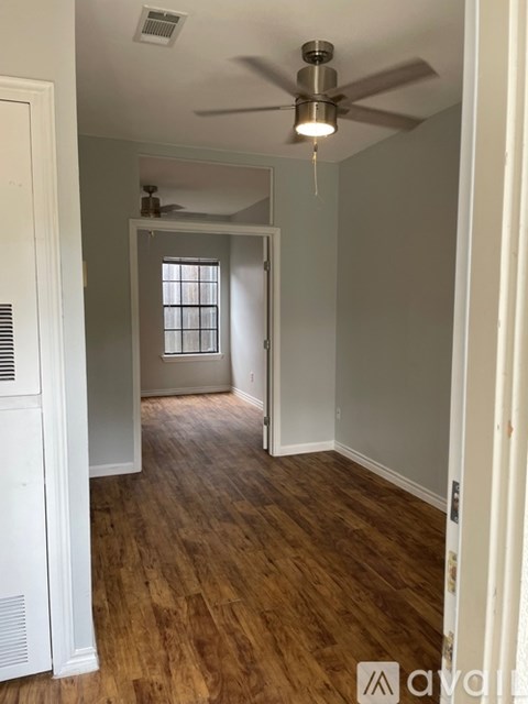 A room with a ceiling fan and wooden flooring.