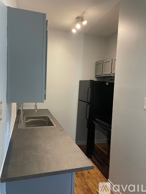 A kitchen with a black fridge and a grey cabinet.