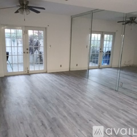 A room with a ceiling fan and sliding glass doors.