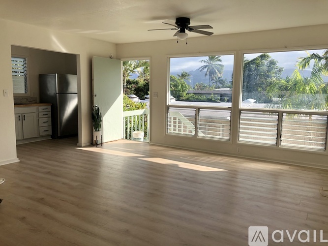 A spacious living room with a ceiling fan and sliding glass doors leading to a balcony.
