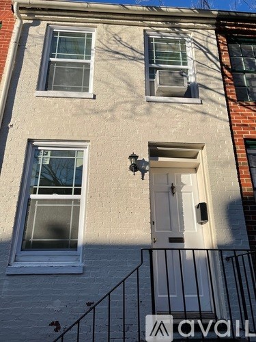 A white door with a black railing is on the right side of a building.