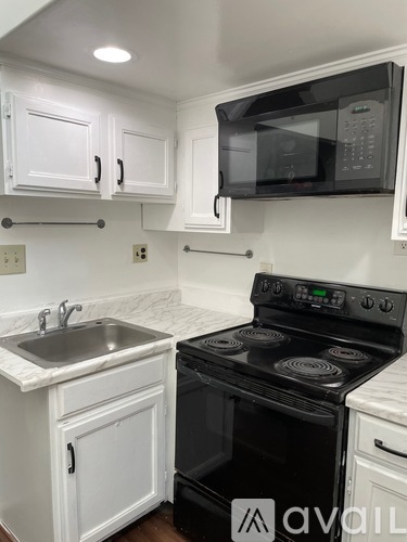 A kitchen with white cabinets and a black stove top oven.