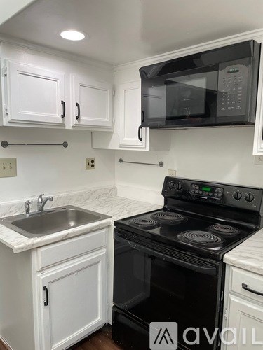 A kitchen with white cabinets and a black stove top oven.