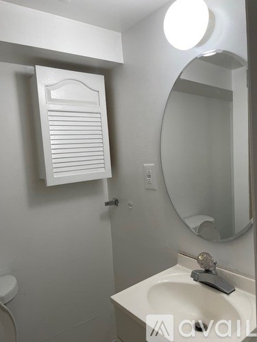 A white bathroom with a sink, mirror, and towel rack.