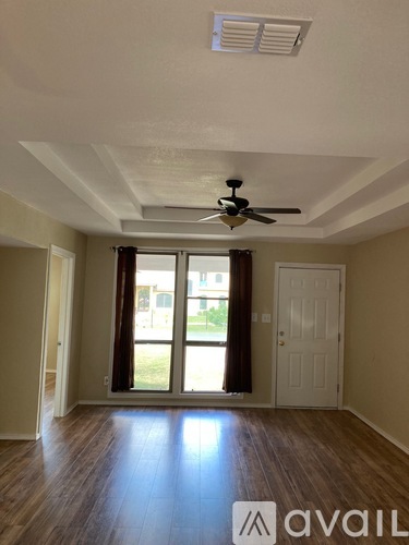 A room with a ceiling fan and sliding glass doors.