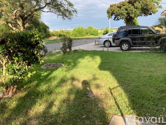 A black SUV is parked in a driveway with a white car in the background.