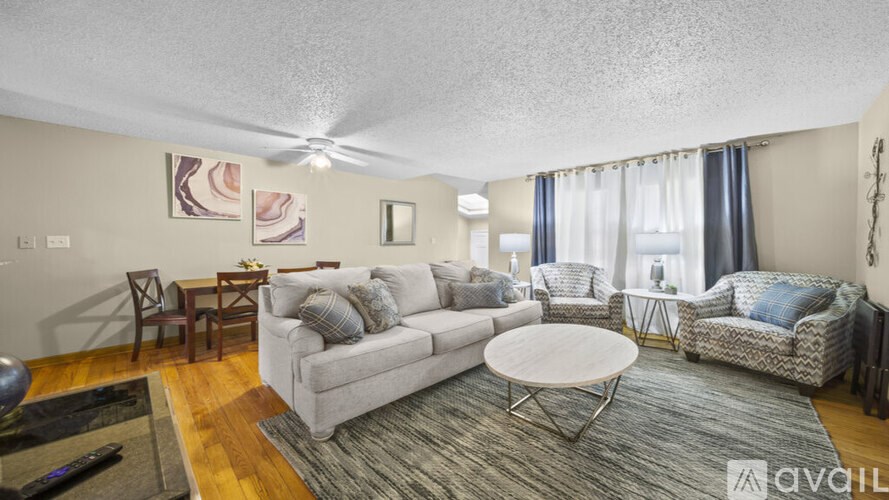 A living room with a white sofa, a grey armchair, a white coffee table, and a wooden floor.