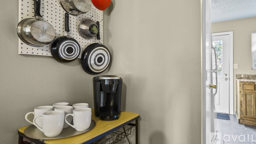 A coffee station with a coffee maker and cups on a table.