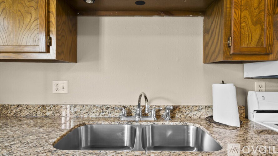 A kitchen sink with a faucet and a white paper towel dispenser.