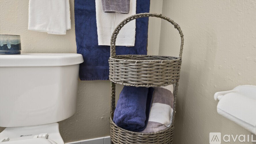A wicker basket filled with towels and a glass of water sits on a bathroom counter.
