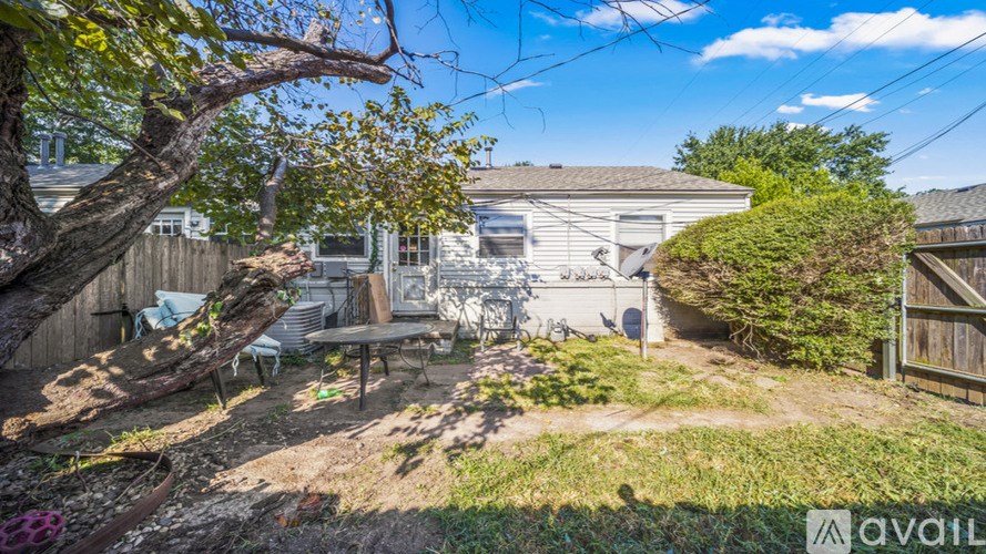 A backyard with a tree, a bench, and a fence.