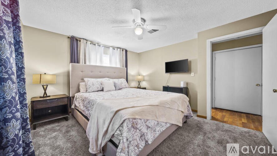 A bedroom with a large bed and a flat screen TV mounted on the wall.