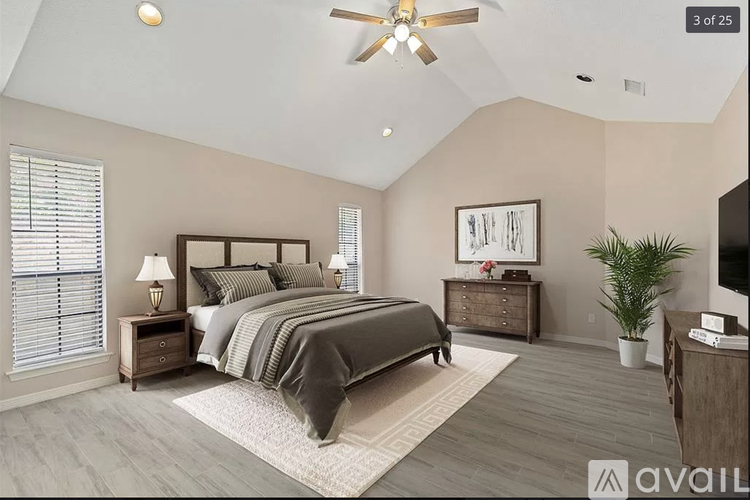 A bedroom with a large bed, a ceiling fan, and a plant.